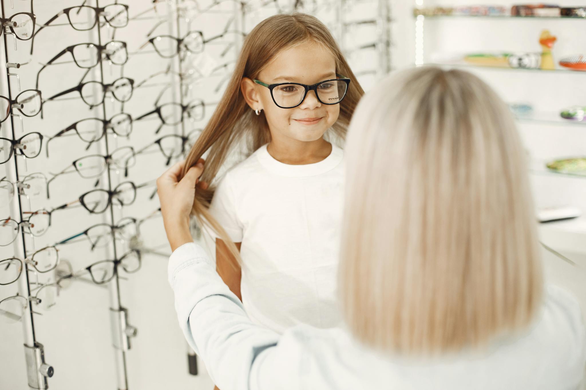Smiling young girl with eyeglasses in an optical store. Professional eyewear fitting service.